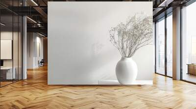 A white vase with white flowers on a white table in front of a white wall. Wall mural