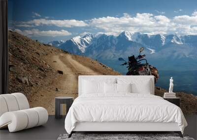 Motorcycle enduro traveler with suitcases standing alone on yellow stone extreme road path on the background of  high snow glacier ranges Altai mountains Siberia Russia Wall mural