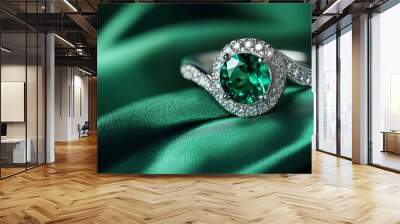 A green emerald fashion engagement diamond ring set against a green satin background. close-up of tasteful female jewelry. discernible focus Wall mural