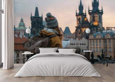 A tourist with a backpack in front of a beautiful old architecture in Prague in the Czech Republic. She looks at the map Wall mural