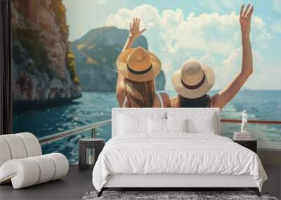 Back portrait of two female friends sitting on boat, waving with hat while talking and enjoying looking at seaside. Sisters finally took vacation to visit their mom who lives in Italy Wall mural