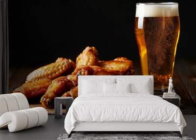 glass of fresh beer and fried chicken wings on wooden table on black background  Wall mural