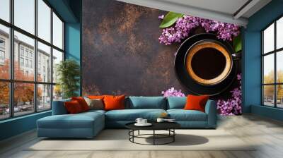 Top view of a black coffee cup on a dark table with purple lilac branches in bloom. Feeling of spring Wall mural