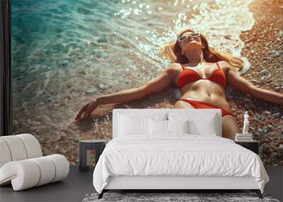 Young woman in red bikini on Beach. Girl lying on pebble beach and enjoying sun. Happy lady in bathing suit chilling and sunbathing by turquoise sea ocean on hot summer day. Close up Wall mural