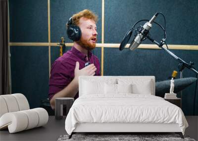 Expressive face of bearded man with red curly hair wear headphones near microphone who makes professional dubbing on a voice recording studio Wall mural