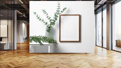 Blank frame mockup for artwork, quote or photo on white wall with natural eucalyptus twigs. Wall mural