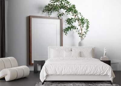 Blank vertical frame mockup for artwork or picture on white wall with eucalyptus twigs. Wall mural