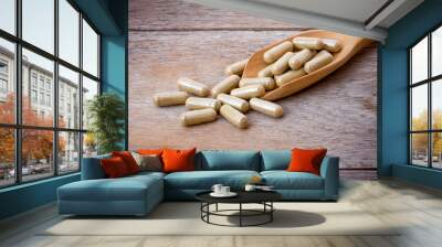 Close-up medicine herbal capsules pill in wooden spoon isolated on old wood table background. Wall mural