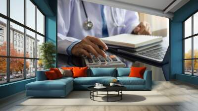 doctor using calculation machine at office desk. Wall mural