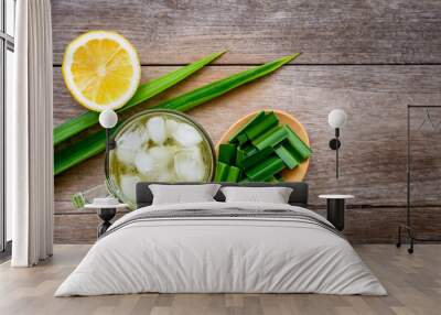 Glass of water pandan juice with green pandan leaf sliced and yellow lemon  isolated on wood table background. Natural herbal plant, fragrant screw pine and healthy drinks concept. top view. Flat lay. Wall mural