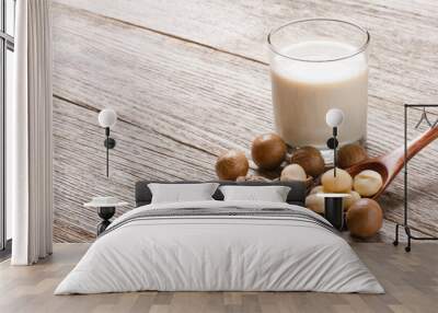 Macadamia milk with macadamia nuts isolated on wooden table background. Wall mural