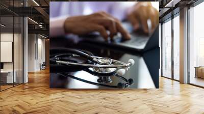 Male doctor typing on a laptop computer. Wall mural