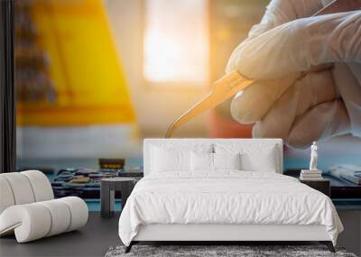 Technician man hand repairing the motherboard of cellphone with forceps in lab room. Wall mural