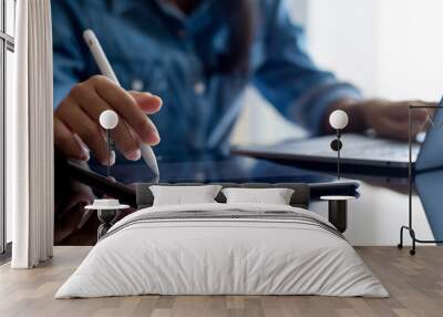 Young business woman hands holding electronic pen ( stylus pen ) and working on black digital tablet pc with laptop computer on the desk at modern home office. Remote working, online learning concept. Wall mural