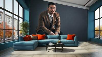 Keep confidence in your stride as you proceed. Studio portrait of a handsome young businessman sitting on a chair against a dark background. Wall mural