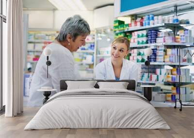 Pharmacist explaining medicine to a woman in the pharmacy for pharmaceutical healthcare prescription. Medical, counter and female chemist talking to a patient about medication in a clinic dispensary Wall mural