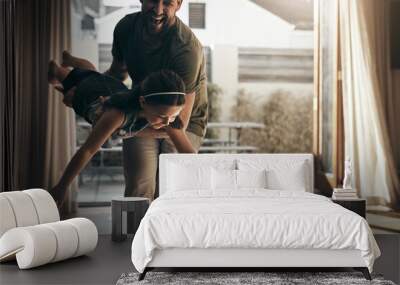 Give them wings and teach them to fly. Shot of a young man enjoying playtime with his daughter at home. Wall mural