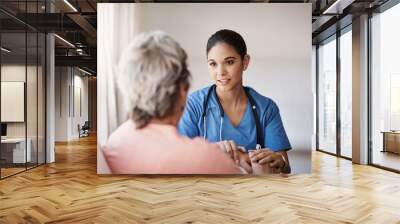 Im here for you...always. Cropped shot of an attractive young nurse holding a senior womans hands in comfort. Wall mural