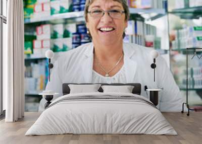 Speak to me for all of your health related queries. Portrait of a happy mature woman working in a pharmacy. Wall mural