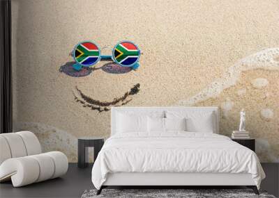 A painted smile on the sand and sunglasses with the flag of South Africa. The concept of a positive and successful holiday in the resort of South Africa. Wall mural