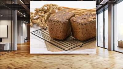 Two fresh loaves of rye bread on the background of spikelets. Wall mural