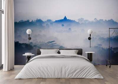 The sun rises on a foggy morning over Borobudur temple near Yogyakarta, Indonesia. Wall mural