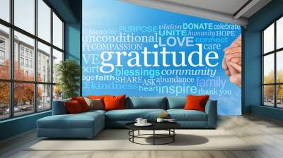 Thanksgiving Togetherness -  Male hands  cradling female cupped hands on a wide blue sky background with a GRATITUDE word cloud and large sun burst in top left corner Wall mural