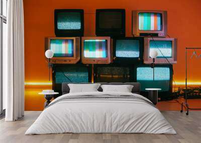 Old vintage tvs on a floor in a room with colored neon light. Wall mural