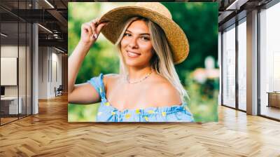 Portrait of attractive young woman in straw hat outdoors in summer sunny day. Wall mural