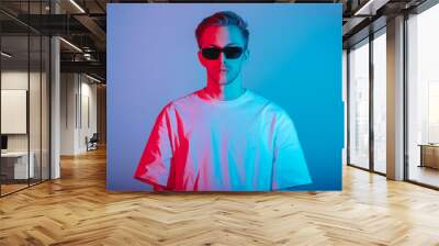 Portrait of fashion young man in white t-shirt and black sunglasses in red and blue neon light. Wall mural