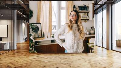 portrait of young caucasian woman in glasses standing on the kitchen at home with christmas decorati Wall mural