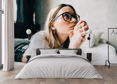 Young bored millennial woman lying on a bed alone at home. Fatigue or emotionally exhausted concept Wall mural