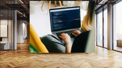 Young woman mobile developer writes program code on a computer, programmer work. Wall mural