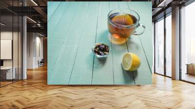 Glass cup of black tea and lemon on a mint-colored wooden table Wall mural