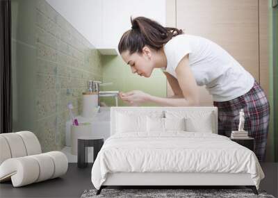 Woman splashing face with water above bathroom sink Wall mural