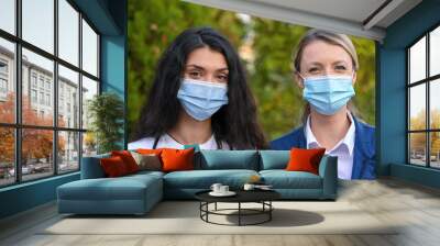 Female medical specialists. Female doctors portrait. Pandemic female heroes. First aid ambulance. Doctors wearing masks. Nurses during pandemic. Two powerful females. Wall mural