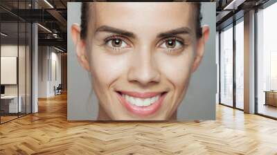 Close-up portrait of a young woman with a genuine, joyful smile against a neutral background Wall mural