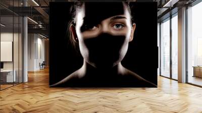 studio portrait of a beautiful young woman with shadows on her face, against dark backgroung Wall mural