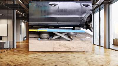 The car lifted by a pneumatic jack, wheel replacement. Wall mural