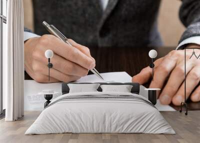 a businessman sits at an office desk and signs a contract with a ballpoint pen Wall mural