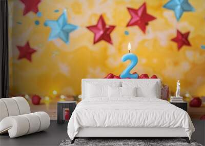 Strawberry cake with blue candle number 2 surrounded by stars and garland on yellow background Wall mural