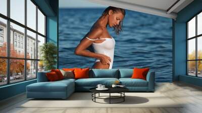 Beautiful woman in swimsuit posing in blue sea water. Tanned sexy woman in bikini Wall mural