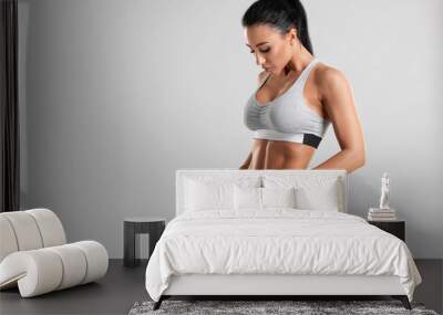 Fitness woman showing abs and flat belly, isolated on gray background. Beautiful athletic girl, shaped abdominal Wall mural