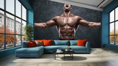 Muscular man showing muscles on wall background. Strong male naked torso abs Wall mural