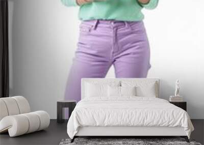 A woman in a green shirt and purple pants holding her phone. AI. Wall mural