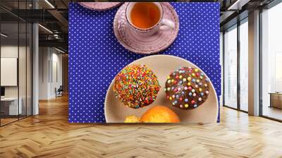 Baking with tea and chocolate on the table.  Two cups of tea with cupcakes and chocolate with a multicolored powder on the table. Wall mural