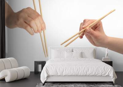 Female hand holding wooden sushi chopsticks isolated on white background. Wall mural