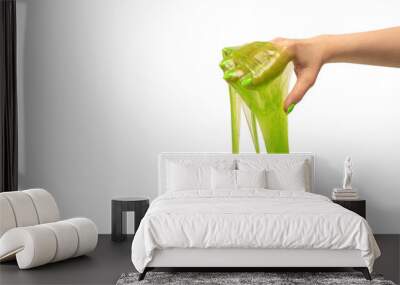 Green slime toy in woman hand with green nails isolated on a white background. Wall mural