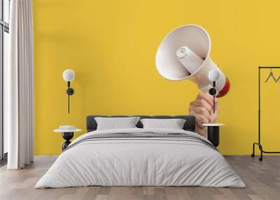 Megaphone in woman hands on a yellow background. Wall mural