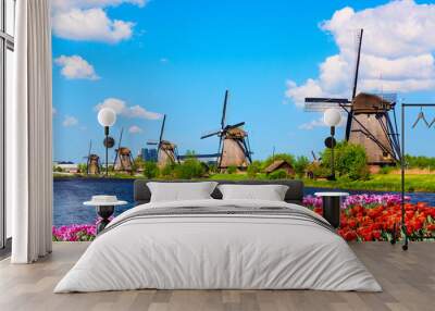 Colorful spring landscape in Netherlands, Europe. Famous windmills in Kinderdijk village with a tulips flowers flowerbed in Holland. Famous tourist attraction in Holland Wall mural